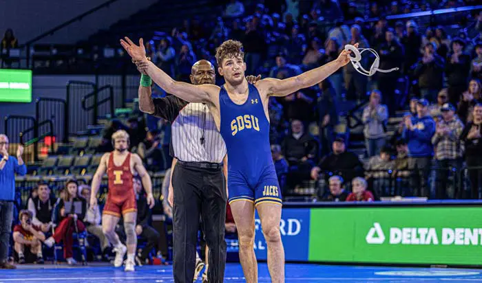 Wrestler standing with ref with arms open wide in victory